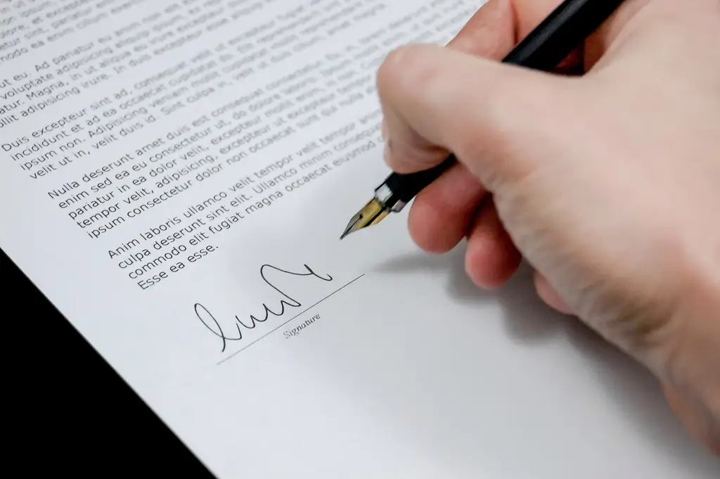 A hand signing a contract, fixing a lump-sum fee against a defined scope of work