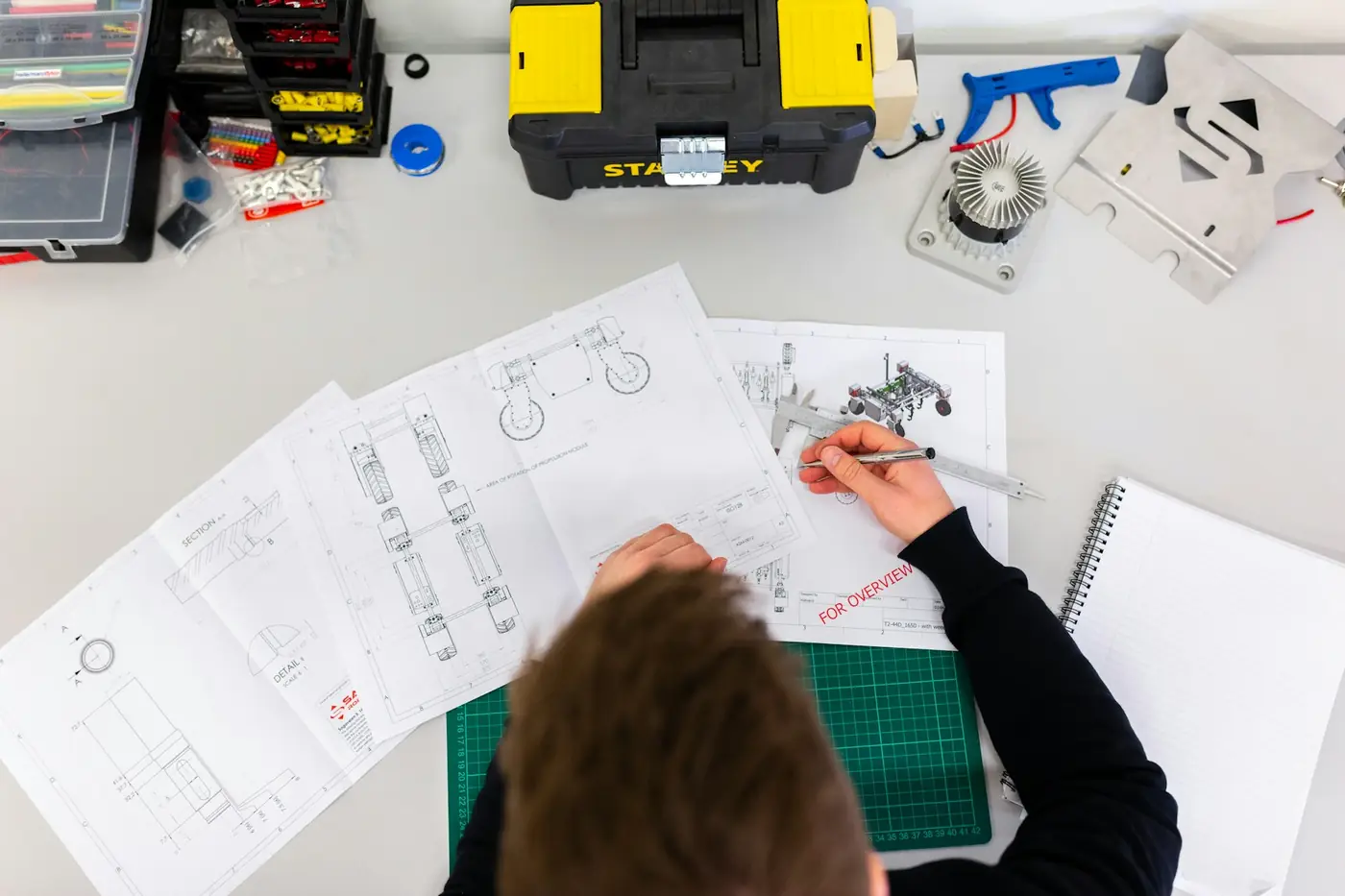 Seen from above, a designer drafting plans on a cutting mat, deep in a high-attention stage