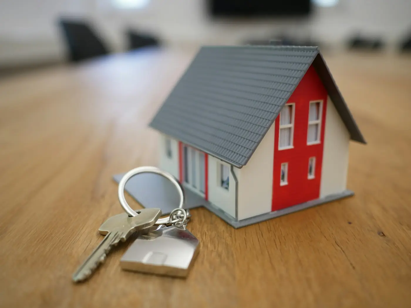A small model house beside a set of keys on a table, a unit waiting for its next tenant