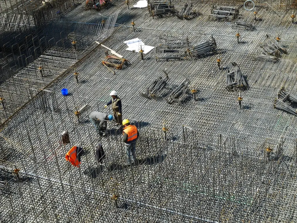 Workers on a dense reinforcement grid seen from above, steel that will soon be covered by concrete